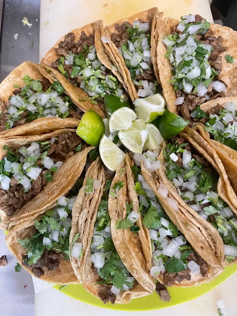 Platter of street tacos with cilantro, onion and lime wedges